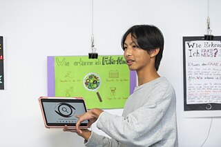 Ein Junge hält ein iPad in der Hand mit dem Logo der Taiwan Fact Checking Seite.