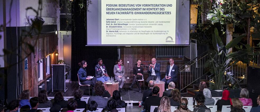 6 people on stage, audience listens