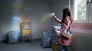 Mädchen in leerem Zimmer, mit Lupe, durch die Sonnenstrahlen scheinen 