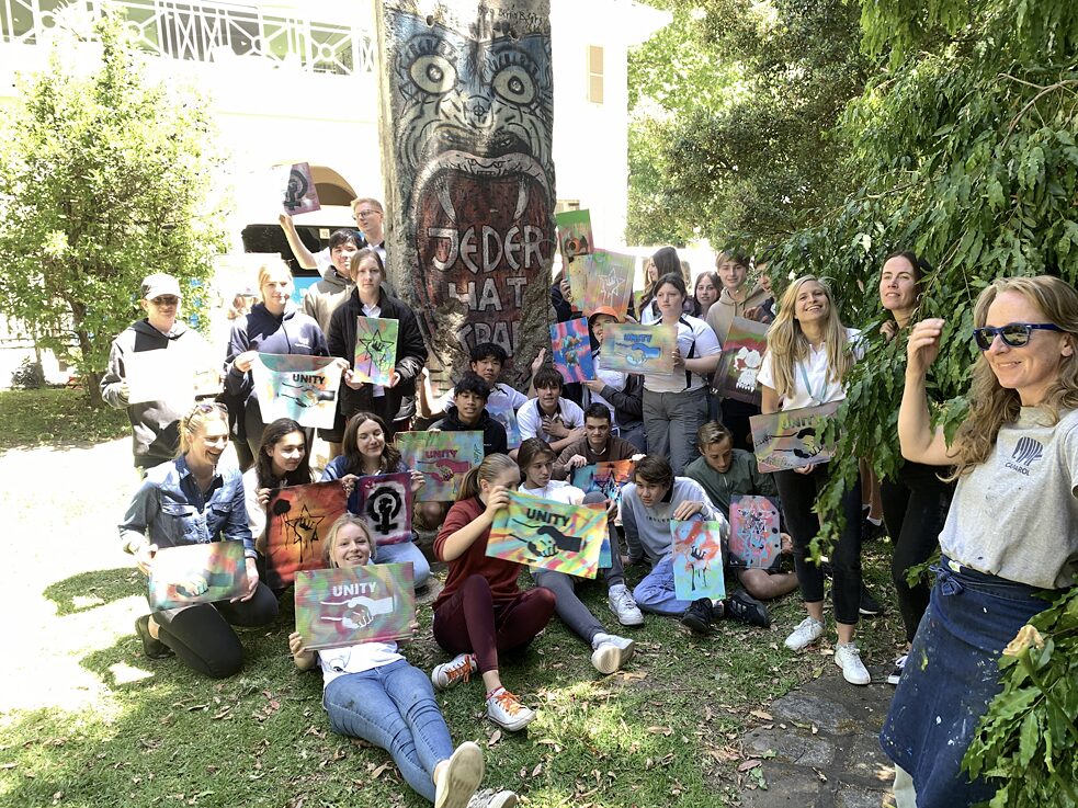 Graffiti spray cans stand on the ground in front of a wall