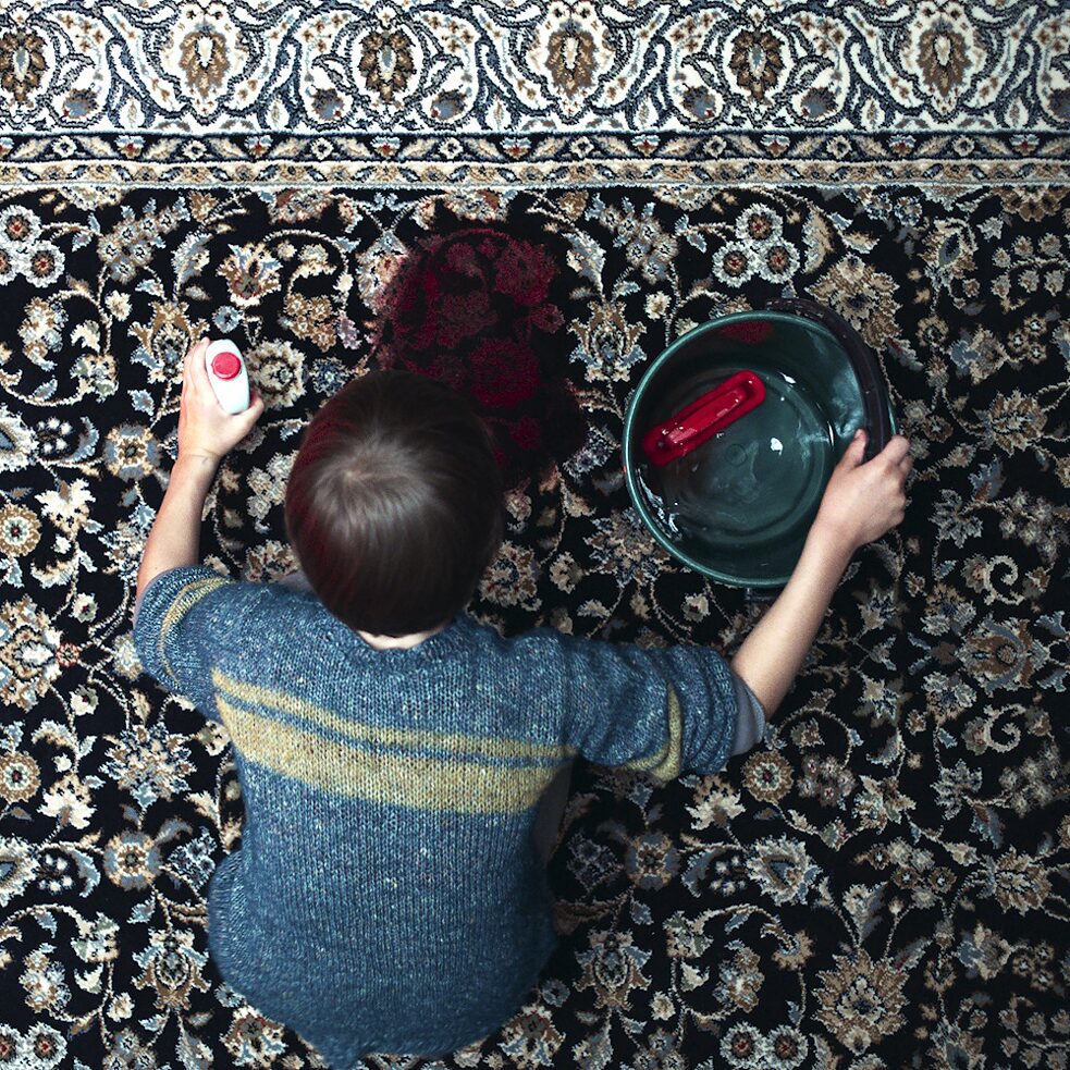 Jonathan (Sammy Schrein) cleaning a blood stain on the carpet. Stillframe from the Netflix Germany series "Liebes Kind / Dear Child"
