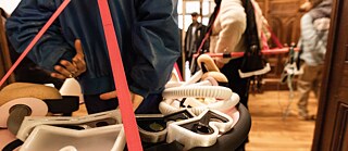 Eine Frau trägt einen Ring um den Bauch, darin finden sich Taucherbrillen, Schnorchel und andere Gegenstände.