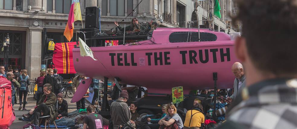 Photo is showing a public demonstration using a pink submarine with the slogan “Tell the truth”. 