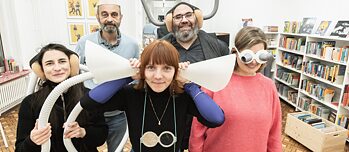 Das RESONANCE-Tandem aus Nancy mit zwei Mitgliedern des Theaterkollektivs TOUT VA BIEN! Die Personen tragen skurrile Brillen und Kopfbedeckungen, eine Person hält sich Trichter an die Ohren