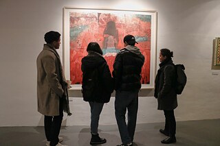 Four visitors stand contemplating Mohsin Taasha's painting