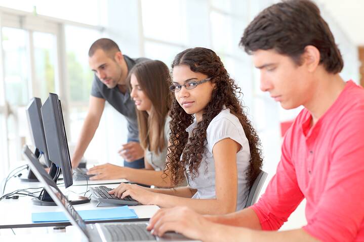 Lehrperson betreut Schülerinnen und Schüler bei der Arbeit am Computer