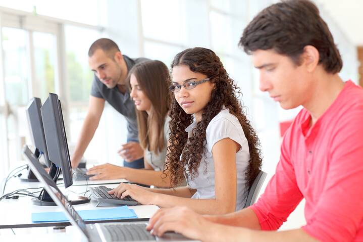 Teacher supervising pupils working on the computer