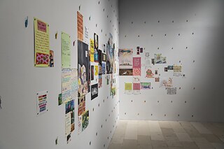 Colourful drawings and texts on paper are placed as a collage on two cornered walls