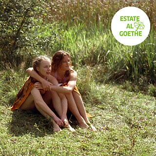Filmstill aus „Mitte Ende August”: zwei Mädchen sitzen auf einer Wiese