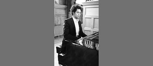 Adrian Henke spielt auf einem Blüthner-Klavier. Schwarz-Weiß-Foto