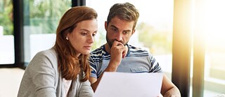 Ein Student im Sprachkurs am Goethe-Institut. Deutschübung mit Lehrkraft. Er macht eine Übung am Smartboard. Die Lehrerin begleitet die Übung. Aufnahme seitlich.