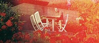 Ein Mann sitzt auf einer Garten-Terrasse