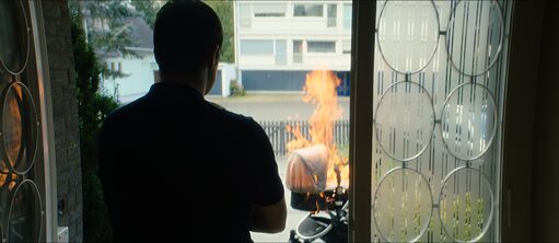 Man looking outside a decorated doorway at a burning baby carriage