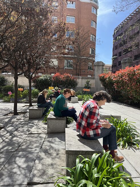 Die Teilnehmenden sitzen im Hof in der Sonne und schreiben einen eigenen Text. 