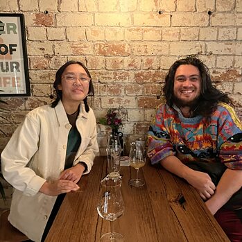 Friends of Goethe Australia Scholars Isabella Alvarades and Andy Butler sit a table in a bar to celebrate their success.