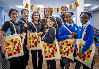 A group of girls is posing with colourful bags from the Goethe-Institut