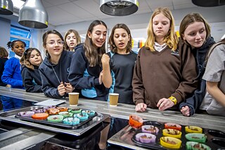 A grou of girls is waiting for their chocolate muffins to cool down