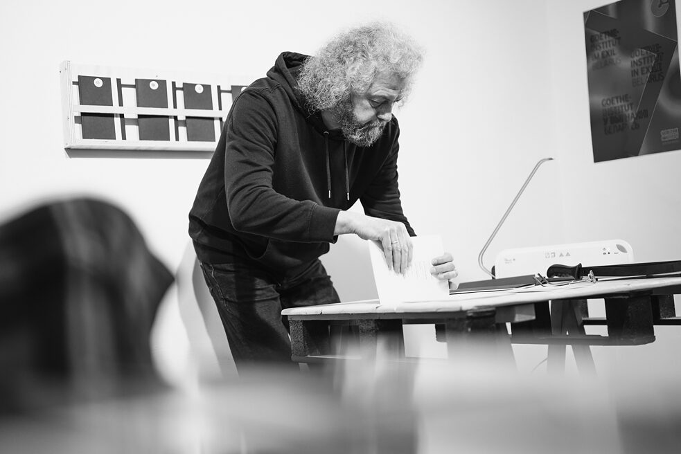 Dmitri Strozew leans over a table and shows the audience how a book is bound