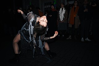 A dancer in a silver dress bends backwards
