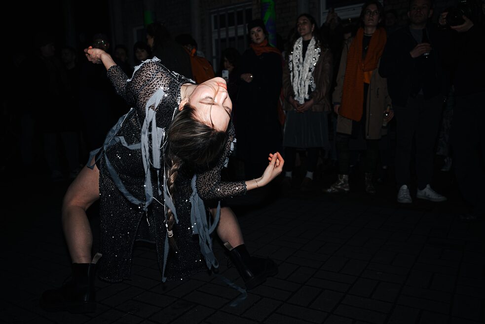 A dancer in a silver dress bends backwards