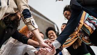 Verschiedene Menschen halten sich an den Händen.