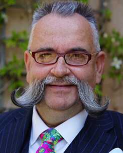 Man smiling wearing glasses and colourful tie