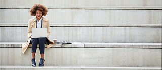 Eine Frau arbeitet vergnügt am Laptop