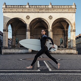 A woman carrying a surfboard at the city center