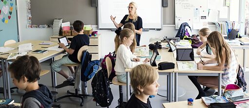 Schülerinnen und Schüler mit Lehrerin im Klassenzimmer
