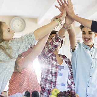 Schüler klatschen im Klassenzimmer die Hände gegeneinander