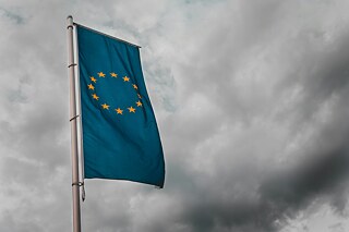 Die Europafahne weht an einem grauen Himmel.