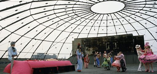 open roof top space with glas cealing and a carnevalesque crowd celebrating