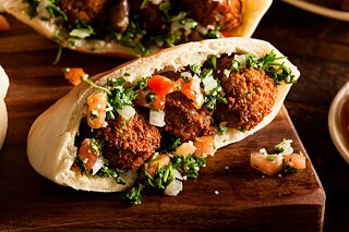 Three falafel in a sandwich lying on a wooden board 