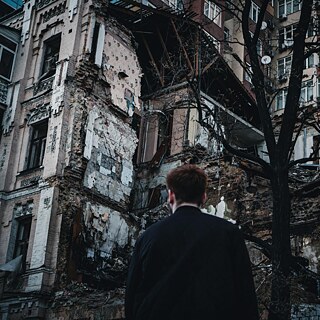 Ein man schaut auf das von einer Rakete zerstörte Gebäude 
