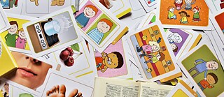 kleine Bildkärtchen liegen verteilt auf einem Tisch, bunt