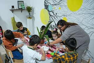 Kinder basteln gemeinsam an einem Tisch