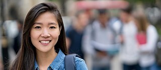 Porträt einer jungen Frau, Close-Up. Der Hintergrund ist unscharf. Die Frau lächelt in die Kamera.