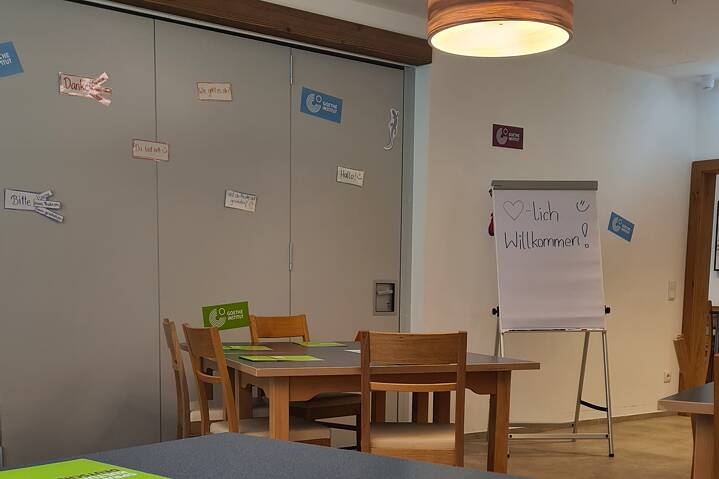 Ein leeres Klassenzimmer. An den Schränken hängen bunte Vokabeln, auf einem Whiteboars steht „Herzlich Willkommen!“