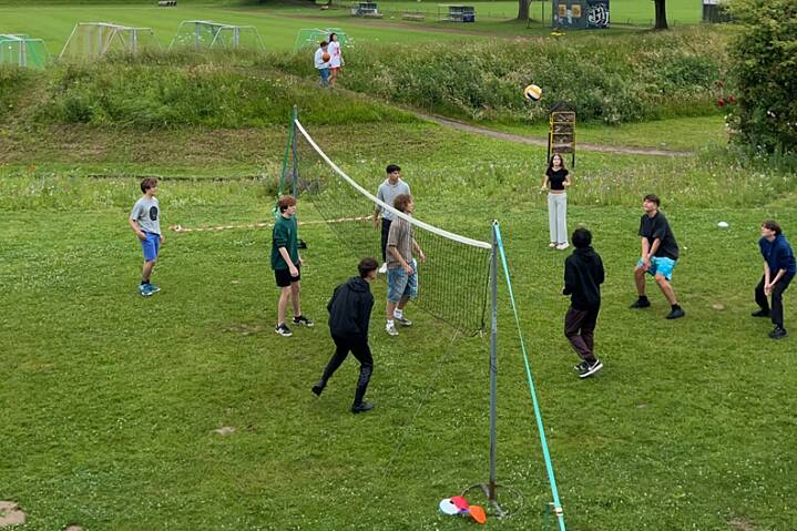 Jugendliche spielen Volleyball auf einer Wiese.