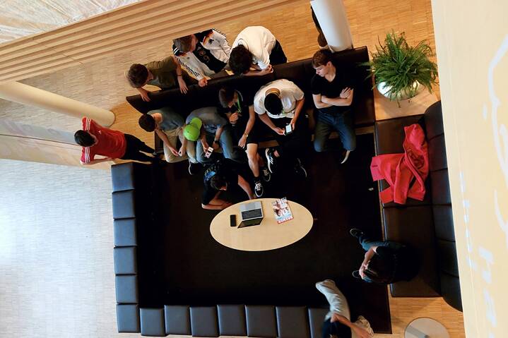 Eine Gruppe Jugendlicher sitzen auf einer Couch und blicken gespannt auf ein Laptop.