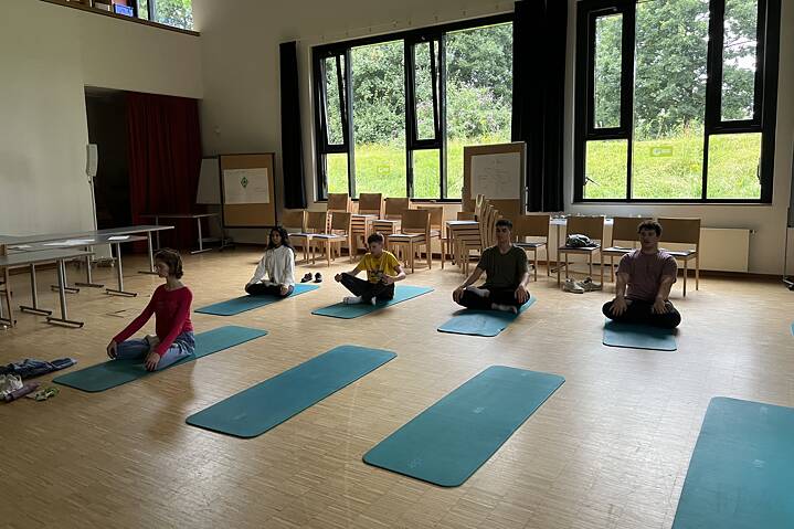 Fünf Jugendliche entspannen auf Yogamatten.