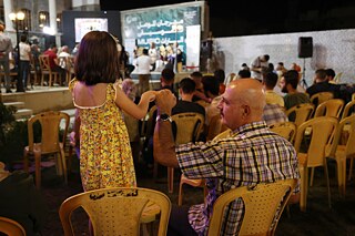 Ein Mann hält die Hand eines Mädchens beim Mosul Music Heritage Festival