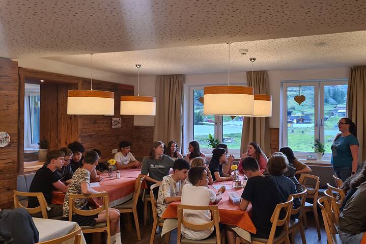 Jugendliche sitzen an langen Tischen und verfolgen Anweisungen.
