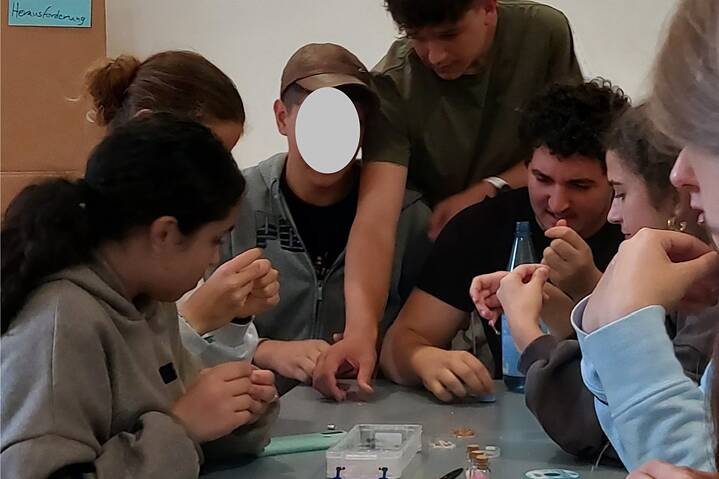 Jugendliche basteln mit kleinen Perlen.
