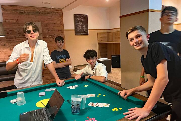 Jugendliche spielen Karten. Auf dem Tisch liegen Spielkarten und Jetons.