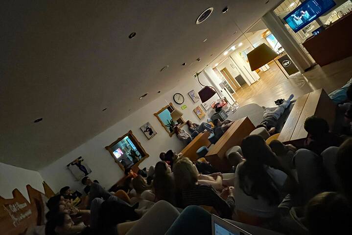 Eine Gruppe Jugendlicher sitzt in einem großen Raum und sieht einen Film.