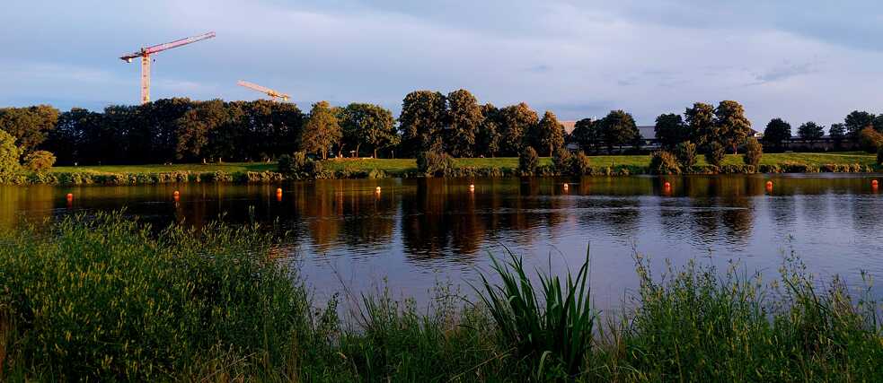 Blick auf den Werdersee in der Abendsonne. Im Hintergrund zwei Baukräne.