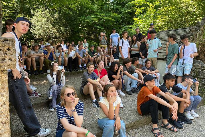 Jugendliche sitzen auf Terrassen und hören gespannt einem Tour Guide zu.
