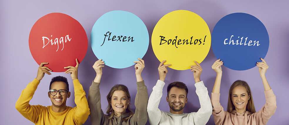 Vier Jugendliche halten bunte Plakate mit Ausdrücken aus der Jugensprache in die Höhe.