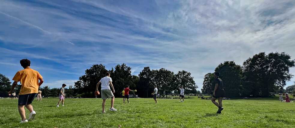 Jugendliche spielen Ball auf einer grünen Wiese.